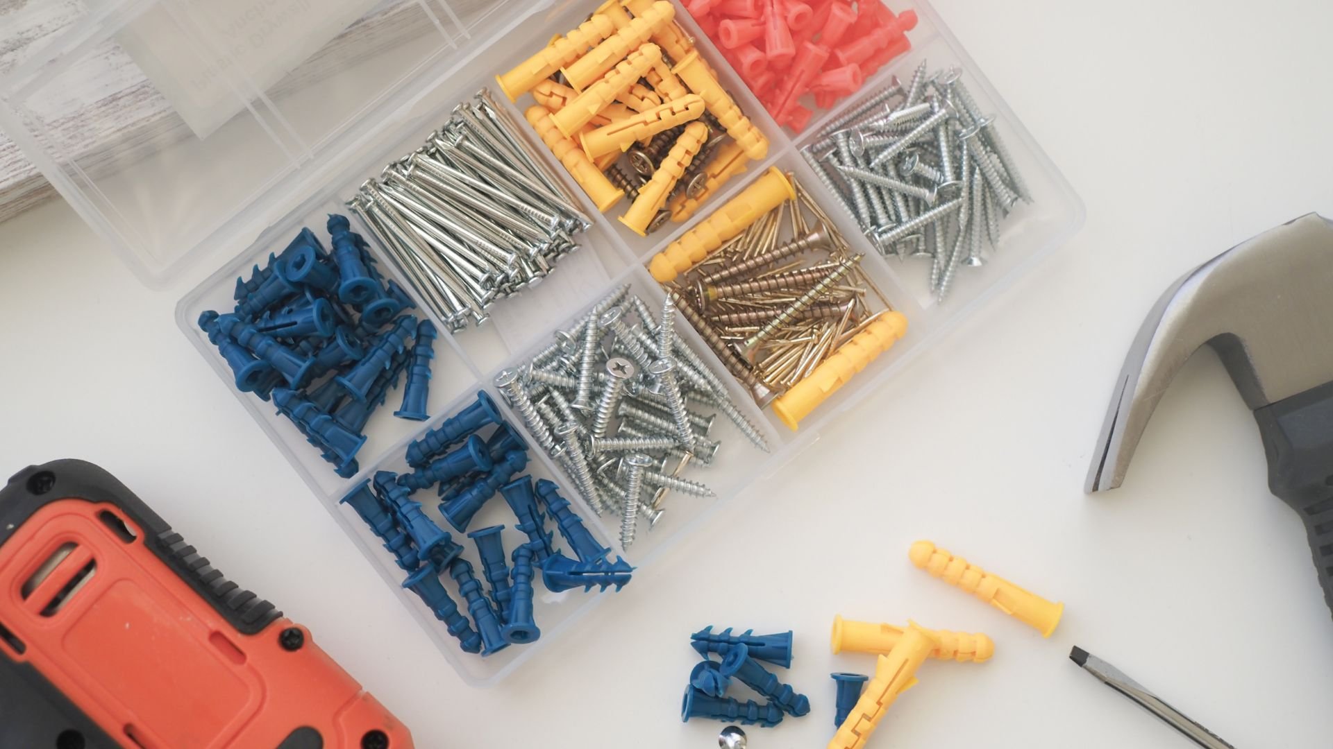 Organized hardware box with screws, wall plugs, and a power drill