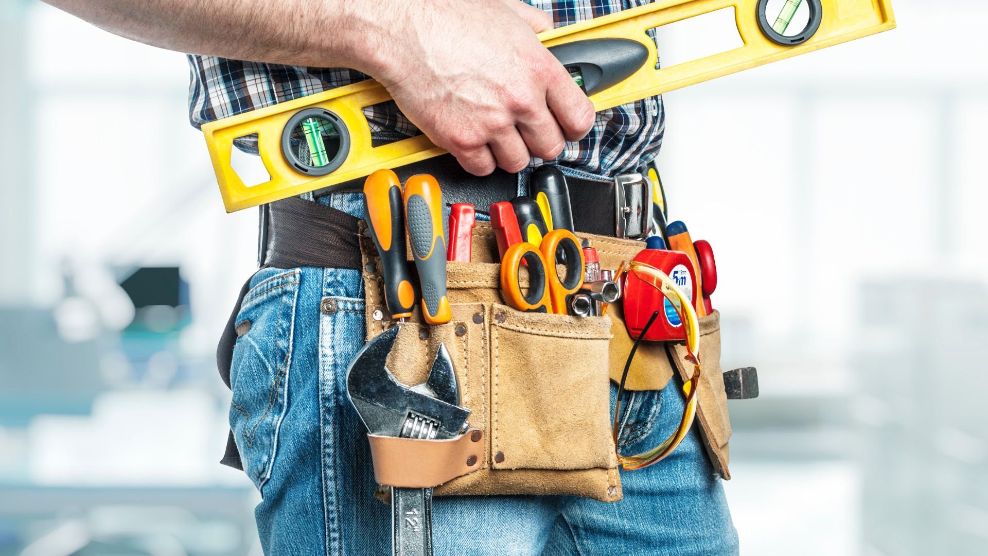 Construction worker with tool belt and level, ready for home repairs